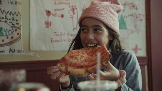 近距离的笑女孩吃一片奶酪披萨/旧金山，加利福尼亚，美国视频素材