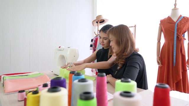 年轻的时装设计师学生缝纫衣服与老师顾问照顾视频下载