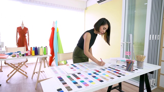 小企业，服装店。年轻的亚洲女人在橱窗服装店工作视频下载