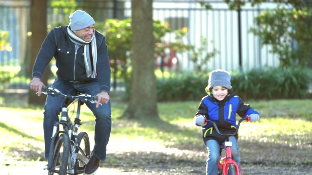 西班牙裔父亲和儿子在公园里骑自行车视频下载