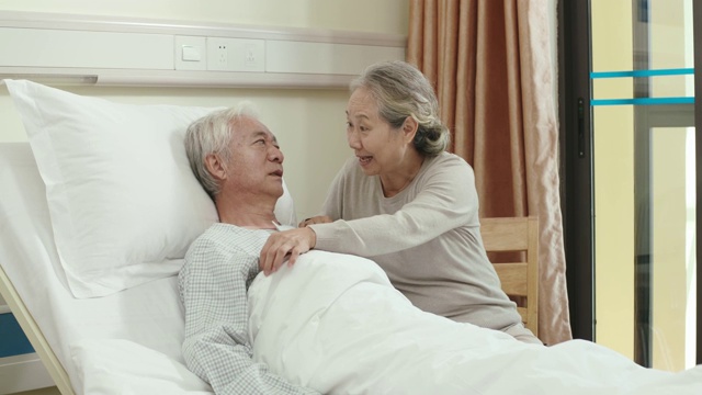 亚洲老妇人在床边与丈夫交谈视频素材