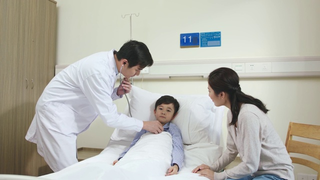 一名亚洲医生正在病房检查儿童病人视频素材