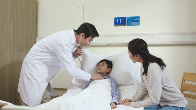一名亚洲医生正在病房检查儿童病人视频素材