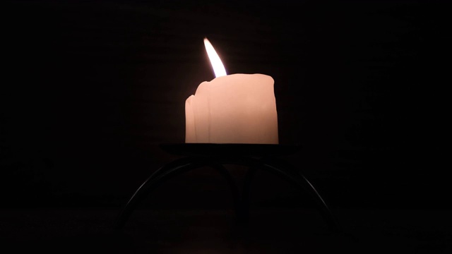 蜡烛在黑色背景上燃烧然后熄灭。关闭了。火焰在气流中摇曳。烛光下的浪漫之夜。视频素材