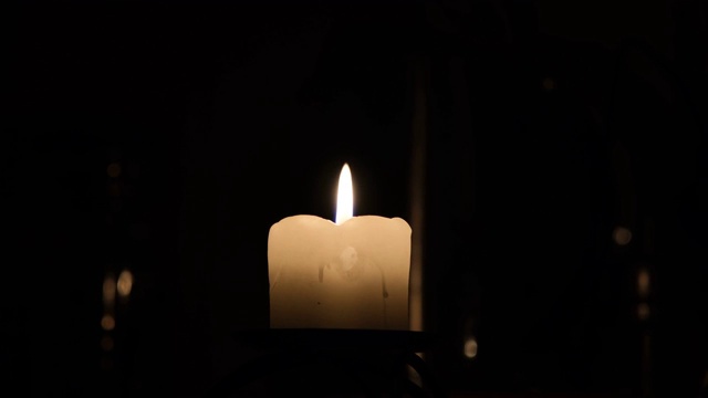 蜡烛在黑色背景上燃烧然后熄灭。关闭了。火焰在气流中摇曳。烛光下的浪漫之夜。视频素材