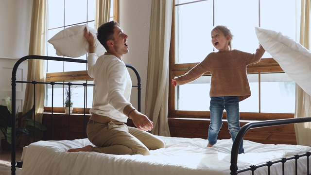 无忧无虑的小女儿和爸爸在床上玩枕头大战视频素材