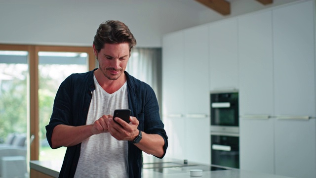 英俊男子用手机在厨房岛视频下载