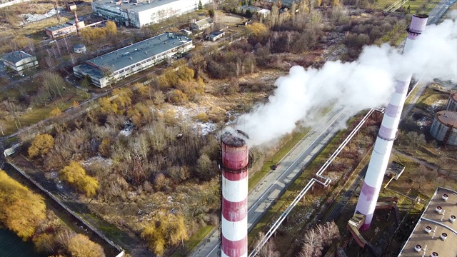 环境污染鸟瞰图:有烟的管道。工业园区有一根红白相间的大管子，浓浓的白烟从工厂的管子里倾泻而出。视频素材