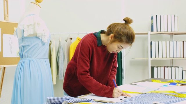 年轻的亚洲时装设计师测量服装上的人体模型在她的家庭办公室，时尚行业，在家里工作，小企业主视频素材
