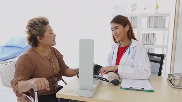医生在医院的办公室里用血压计给老年妇女病人检查视频素材