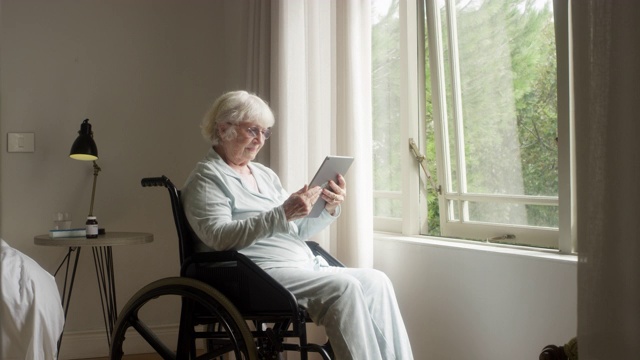 老年妇女在轮椅上使用平板电脑视频素材