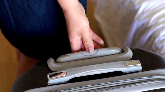 一个女人在酒店房间里拿着一个手提箱的把手的特写。视频下载