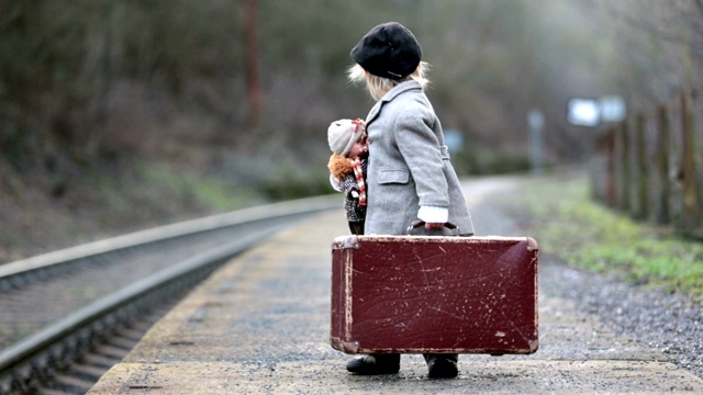 可爱的男孩在火车站，等待火车手提箱和漂亮的古董娃娃视频下载