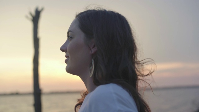 一个嬉皮士给一个美丽的女人戴上一顶帽子，并在日落时分在海滩上亲吻她视频下载