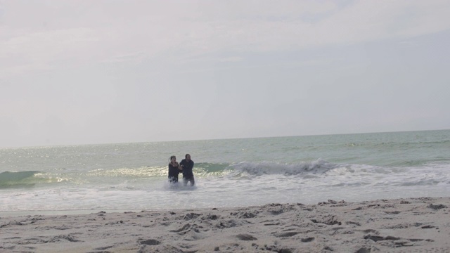 一对美丽的千禧夫妇拍摄了他们穿着衣服在海里跑步的画面视频下载