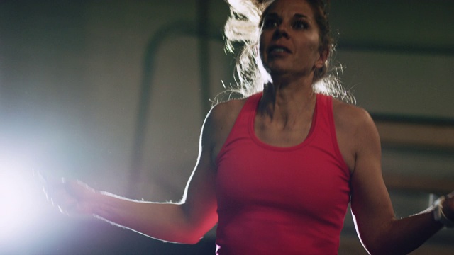 一个四十多岁的白人妇女穿着运动服在室内体育馆跳绳的慢动作镜头视频素材