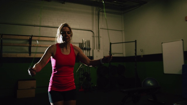 一个四十多岁的白人妇女穿着运动服在室内体育馆跳绳的慢动作镜头视频素材