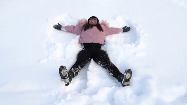 年轻快乐微笑的女孩躺在雪地里，冬天视频素材