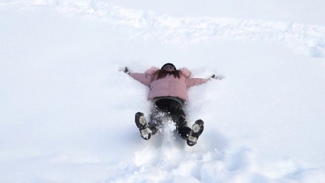 年轻快乐微笑的女孩躺在雪地里，冬天视频素材