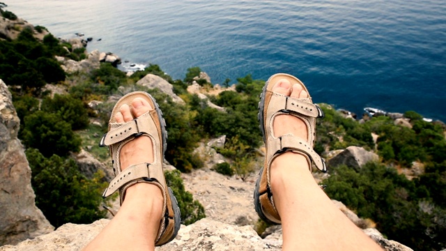男人的腿在棕色的鞋子躺在岩石上的山的背景。克里米亚视频下载