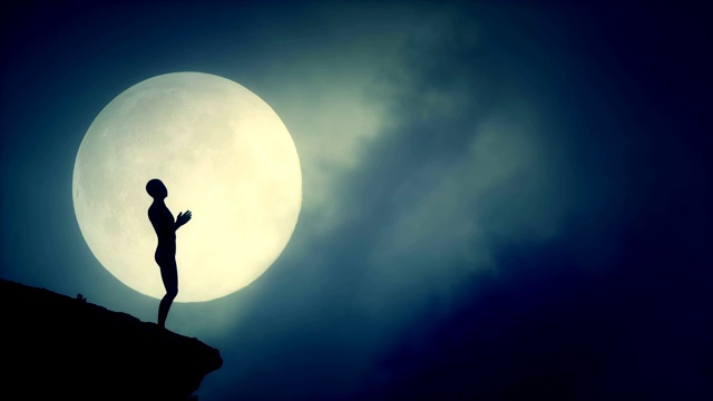 在一个升起的满月之夜，在一个悬崖上手拉手祈祷的剪影视频素材