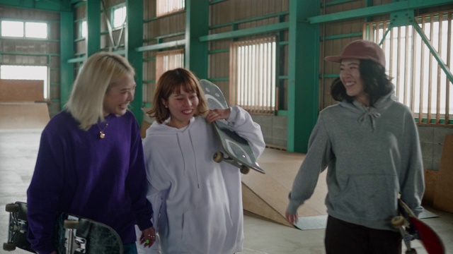 三个日本女滑板手在滑板公园边走边笑视频素材