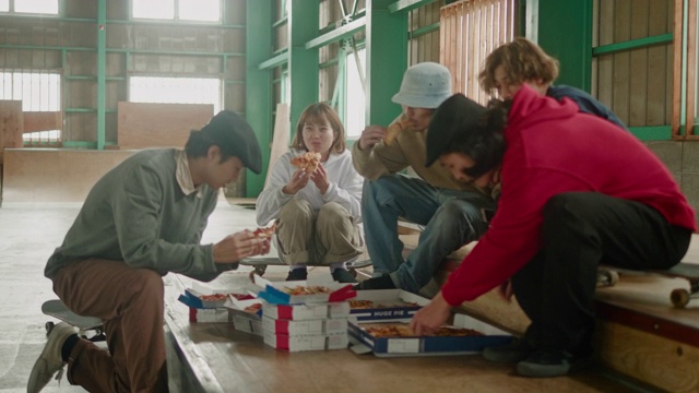 一群年轻的日本滑板爱好者在玩滑板的时候吃披萨视频素材