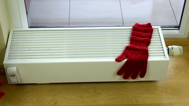 女孩手把红色羊毛手套戴在家里的暖气片上。视频下载