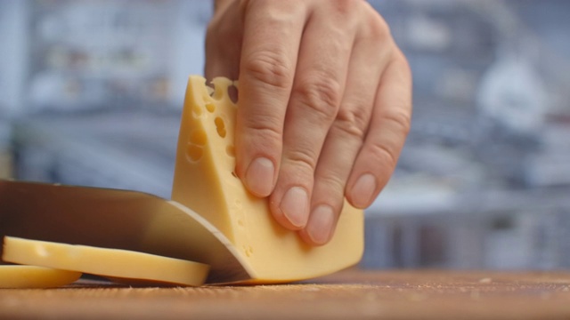 在木板上切黄色有洞的奶酪特写镜头。分解视频下载