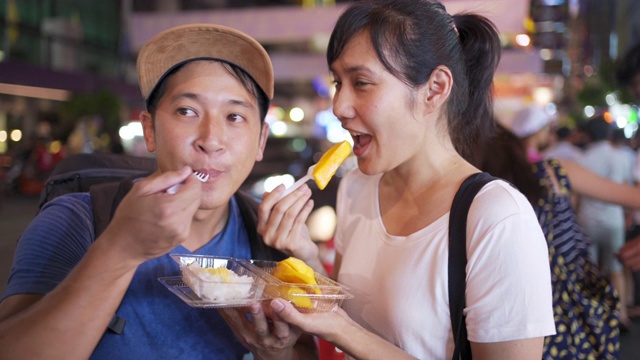 街边小吃-一对年轻夫妇在吃芒果糯米饭，曼谷，泰国视频素材