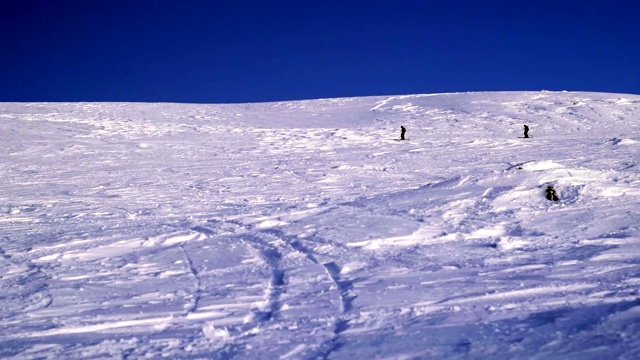 两名滑雪者在山脉的背景下的雪坡上滑行。希比尼，在北方冰雪覆盖的山区里搭便车很危险。视频素材