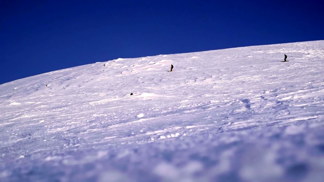 两名滑雪者在山脉的背景下的雪坡上滑行。希比尼，在北方冰雪覆盖的山区里搭便车很危险。视频素材