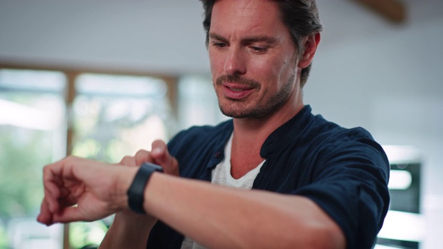 微笑英俊的男人在厨房使用智能手表视频下载
