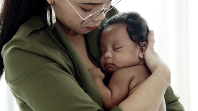 亚洲母亲抱着熟睡的非洲男婴视频素材