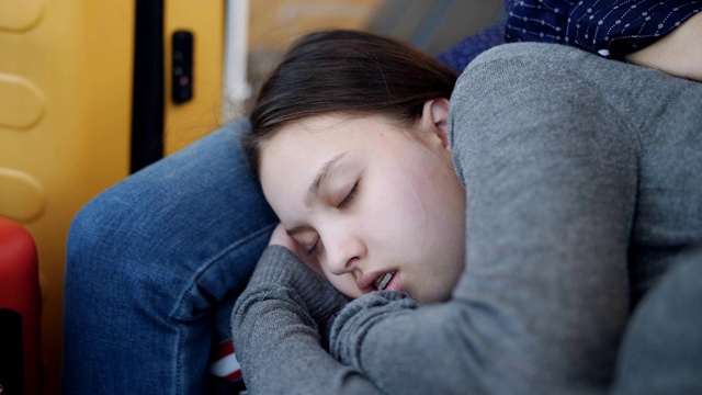 十几岁的女孩睡在旁边的妈妈在候机室的椅子上的特写。航班延误。视频素材