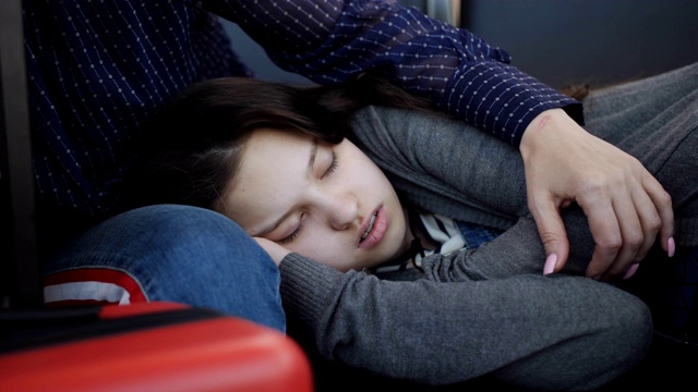 十几岁的女孩睡在旁边的妈妈在候机室的椅子上的特写。航班延误。视频素材
