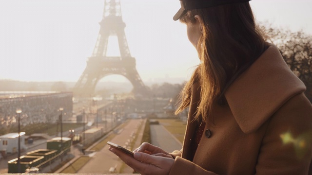 美丽年轻的黑发女商人使用智能手机购物应用程序在史诗般的阳光下的巴黎埃菲尔铁塔观看慢镜头。视频素材