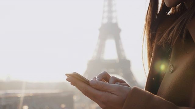 特写手的美丽年轻的博主女人打字的电话在巴黎埃菲尔铁塔城市风景慢动作。视频素材