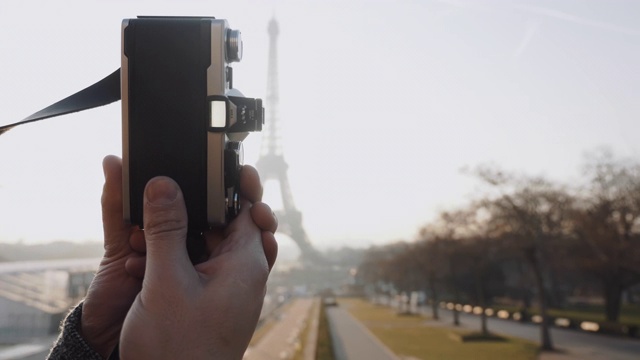 特写摄影师手拍背光日落巴黎艾菲尔铁塔与老式电影相机的慢动作。视频素材