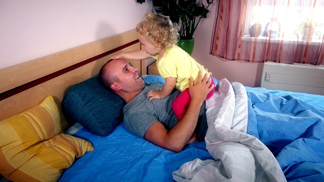 快乐的父亲和女儿在卧室的床上度过了一段时间视频素材