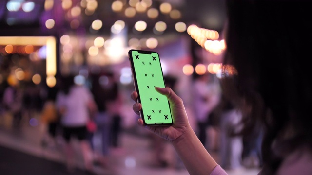 过肩的女人使用智能手机的绿色屏幕在晚上视频素材
