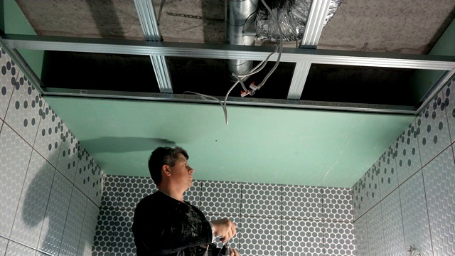 工人正在用螺丝刀将石膏板固定在天花板上。手持视频下载