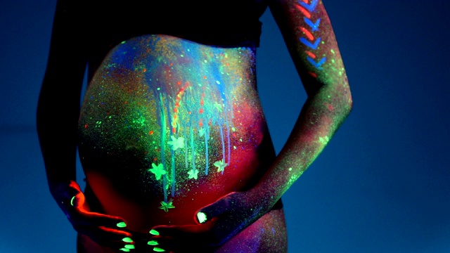在紫外线下涂上荧光化妆品的孕妇身体部位视频下载