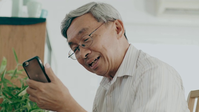泰国祖父用智能手机和妻子聊天，在她的房子里充满爱和思念视频素材