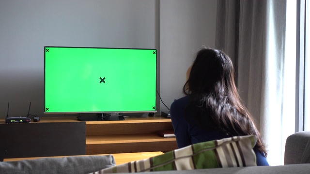 亚洲女人坐在沙发上看电视与色度键在家里视频下载