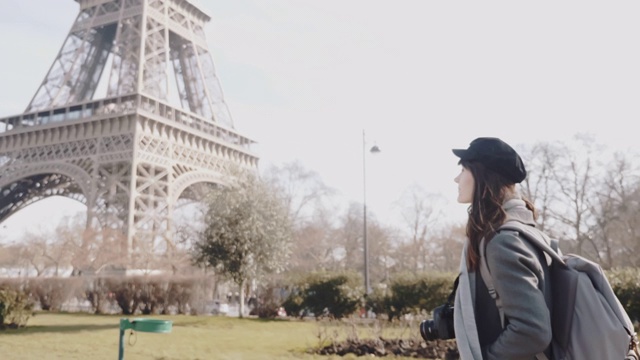 侧视图快乐的自由摄影师女人走在秋天的巴黎街道在埃菲尔铁塔度假慢动作。视频素材