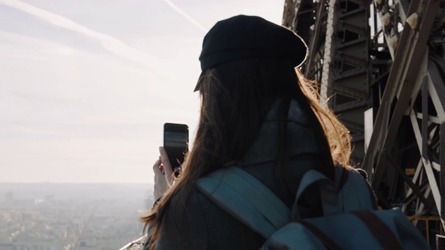快乐微笑的女游客在埃菲尔铁塔上拍下巴黎风景的手机照片，微笑着愉快的慢动作。视频素材