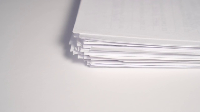 一大捆纸落在一张白色的办公桌上视频素材
