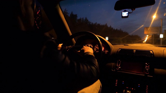 晚上在高速公路上，男性司机手握方向盘驾驶汽车。那家伙晚上开着一辆现代汽车。一个年轻人开着SUV在空旷的路上行驶。特写慢动作视频素材