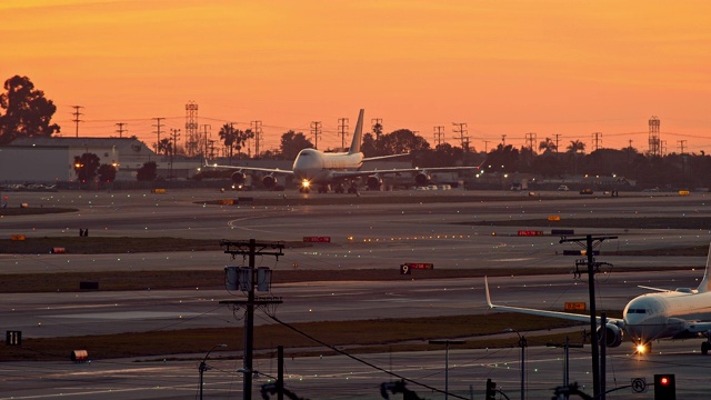 黄昏时分，LS阿特拉斯航空公司的波音747货机在洛杉矶国际机场的停机坪上滑行，联合航空公司的小型客机在前景中滑行视频素材